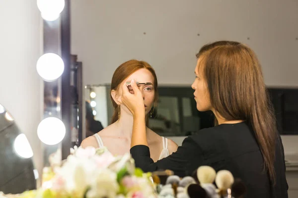 Artista de maquillaje trabaja en su amiga. Gente real. — Foto de Stock