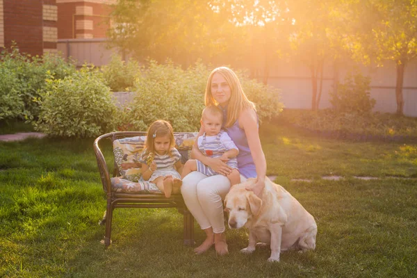 Mor och hennes dotter och son i trädgården med en golden retriever hund — Stockfoto