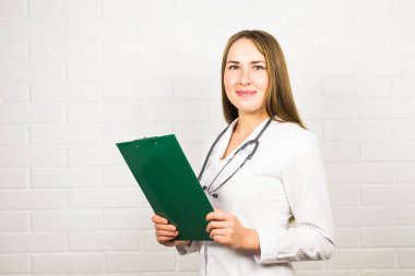 Gülümseyen kadın doktor, üniformalı bir klasörle Hostp 'ta bekliyor..