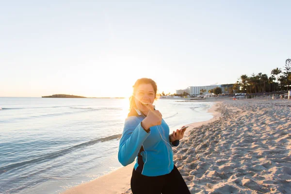 Mujer deportiva motivada haciendo pulgares gesto de éxito después del entrenamiento urbano en la orilla del mar . — Foto de Stock