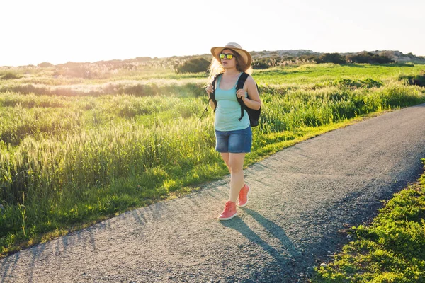 Viagem mochila para o campo europeu, estilo de vida ativo, conceito de férias de verão ativa - Viajante mulher olhando pôr do sol no campo verde — Fotografia de Stock