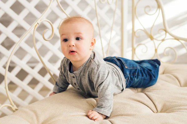 Adorable bebé en el dormitorio soleado. Niño recién nacido relajándose. Guardería infantil para niños pequeños.Mañana familiar en casa. Niñito acostado boca abajo — Foto de Stock