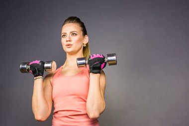 Atletik kadın spor salonunda dumbbells ile yapıyor.