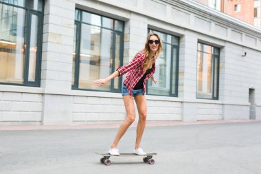 Genç kadın onun kaykay üzerinde sürme. Bayan patenci şehrin üzerinde paten pratik.