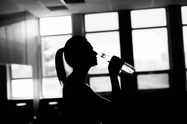 Fitness sportig tjej silhuett utövar och dricka en vatten — Stockfoto