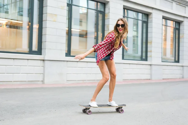 Летние каникулы, экстремальный спорт и люди концепция - счастливая девушка катание на скейтборде по улице города — стоковое фото