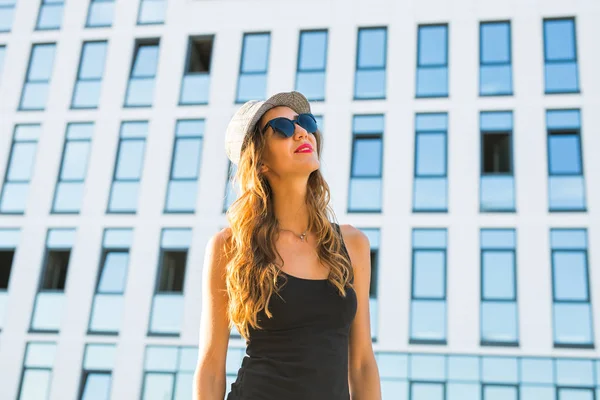 Zonnige levensstijl mode portret van de jonge stijlvolle hipster vrouw lopen op de straat, het dragen van trendy outfit en hoed. — Stockfoto