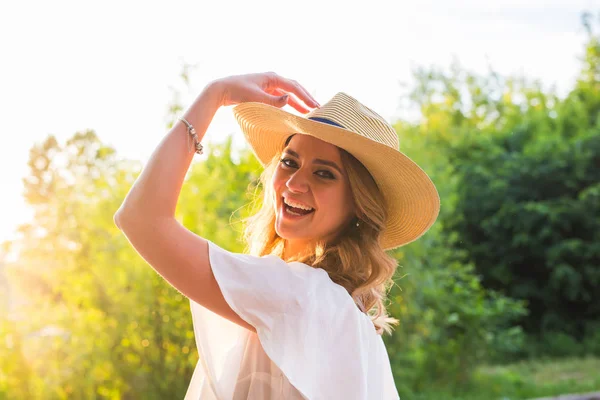 Lachende junge Frau genießt ihre Zeit draußen im Park mit Sonnenuntergang im Hintergrund. — Stockfoto