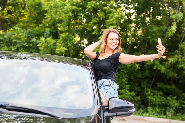 Lächelnde junge Frau macht Selfie-Foto mit Smartphone-Kamera im Auto. — Stockfoto