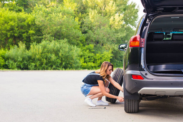 Woman changes the wheel of car on a road