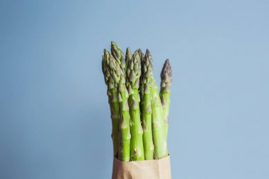 Bohça-in mavi zemin üzerine yeşil kuşkonmaz. Vegan, vejetaryen ve sağlıklı gıda kavramı