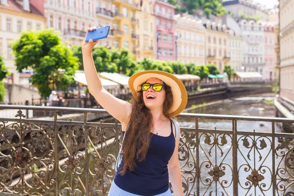 Bonita joven en gafas teniendo paseo en la ciudad europea y haciendo selfie — Foto de Stock