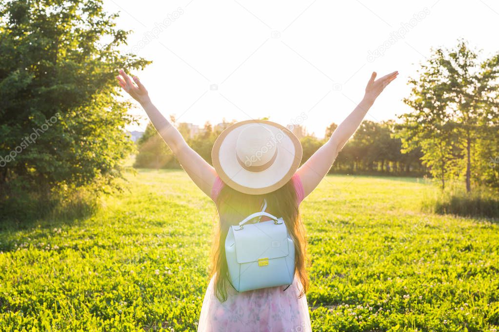 Free happy young woman raising arms watching the sun in the background at sunrise