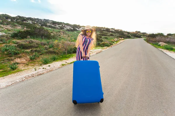 Freedom, travel, vacation and summer concept - Traveler woman walking on the road with suitcases and laughs