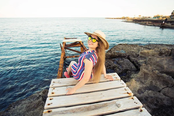 Joven mujer feliz sentada en el muelle de madera y riendo . — Foto de Stock