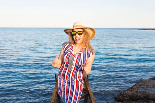 Молода красива жінка показує великі пальці вгору на пляжі — стокове фото