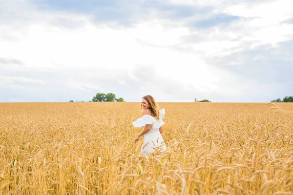 happiness, nature, summer, autumn, vacation and people concept - young woman in the field.