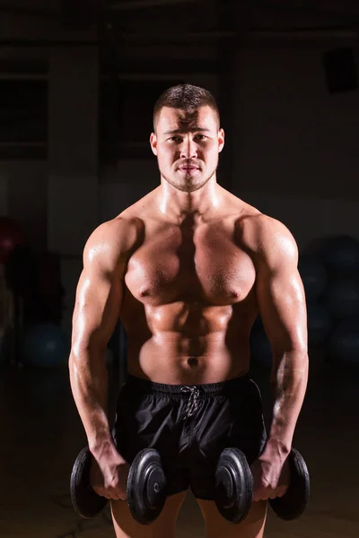 Muscular bodybuilder guy doing exercises with dumbbells. — Stock Photo, Image