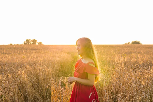 Schöne junge Frau im Weizenfeld bei Sonnenuntergang — Stockfoto