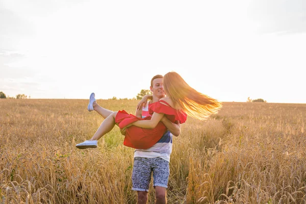 Glada unga par som njuter i vete fält, sommarsäsongen. Solnedgången ljus, utflytning ljus, kopiera utrymme — Stockfoto