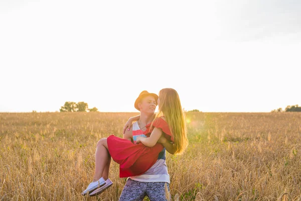 Junge Frau, die von ihrem Freund auf dem Feld getragen wird. Paar hat Spaß im Sommerurlaub. — Stockfoto