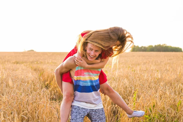 Mutlu çift sahip eğlenceli açık havada buğday alanında günbatımı üzerinde. Neşeli aile birlikte gülüyor. Özgürlük kavramı. Omzunda. — Stok fotoğraf