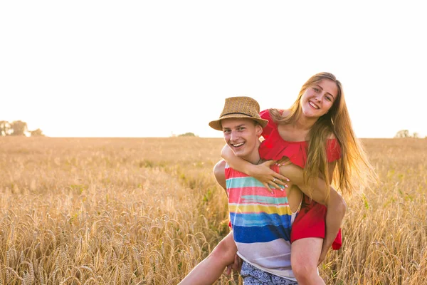 Šťastný pár mají venku Fun na pšeničné pole nad sunset.. Radostné rodinné spolu smát. Koncept svobody. Na zádech. — Stock fotografie