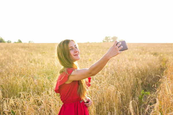 teknoloji, tahıl alan Smartphone'da tarafından kırmızı elbise alma selfie genç kadın gülümseyerek yaz tatil, tatil ve insanlar kavramı-