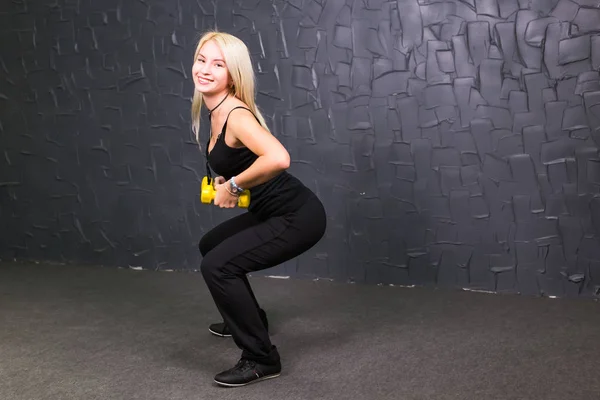 Atraente jovem fitness mulher segurando halteres . — Fotografia de Stock