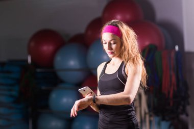 Mutlu genç kadın fitness salonunda etkinlik izleyicisi'ni kullanma