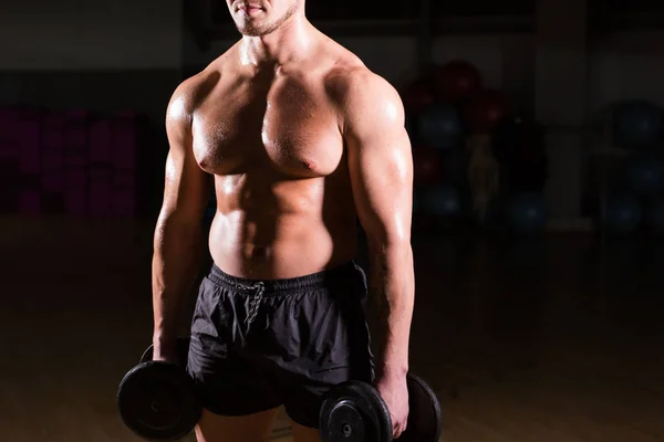 Muscular culturista chico haciendo ejercicios con sombrillas . — Foto de Stock