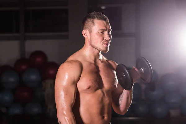 Svalnatý muž cvičení v tělocvičně s činky na biceps, silné mužské nahý trup abs. — Stock fotografie