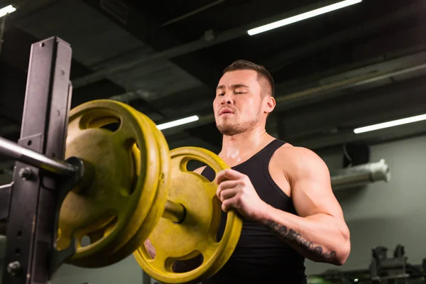 Mladý zdravý muž s velkými svaly drží disku závaží v tělocvičně. Fitness, sport, výcvik, motivace a životní styl koncepce — Stock fotografie
