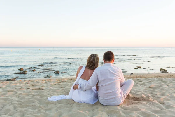 Jovem casal amor sentado juntos na praia — Fotografia de Stock