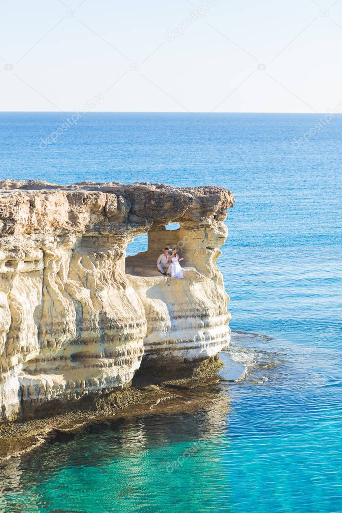 beautiful gorgeous bride and stylish groom on rocks, on the background of a sea, wedding ceremony on cyprus