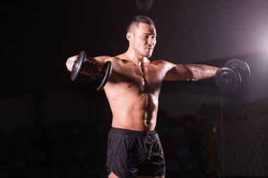 Spor salonunda spor yapan kaslı bir adam, pazularıyla egzersiz yapıyor. Güçlü erkek, çıplak karın kasları var..