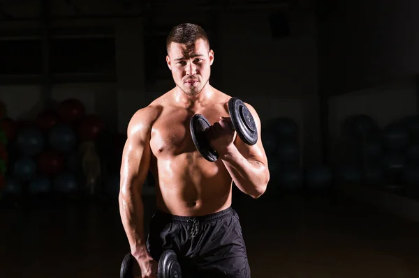 Hübscher, kraftvoller Bodybuilder, der Übungen mit der Hantelstange macht. Fitness muskulöser Körper auf dunklem Hintergrund — Stockfoto