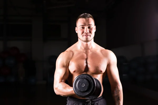 Muskulöser Mann trainiert im Fitnessstudio und macht Übungen mit Kurzhanteln am Bizeps, kräftiger männlicher nackter Oberkörper. — Stockfoto