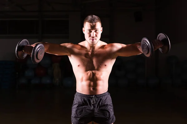 Muscular bodybuilder guy doing exercises with dumbbells. — Stock Photo, Image