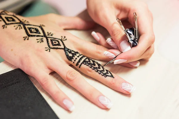 Drawing process of henna menhdi ornament on womans hand.