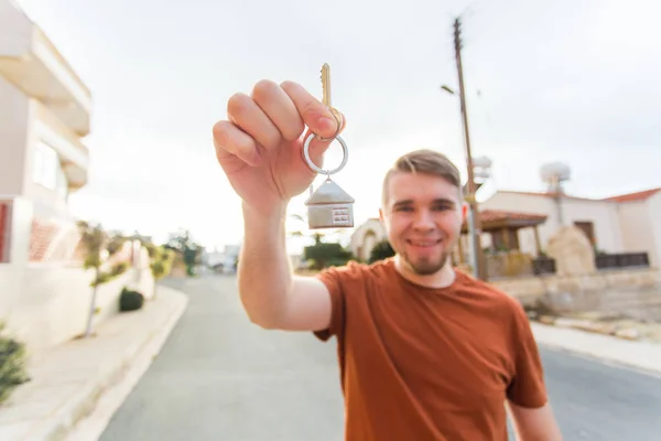 Concept of housewarming, real estate, new home - Young man holding key of new house. — Stock Photo, Image