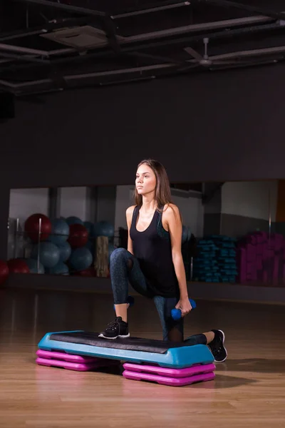 Fitness, sport, výcvik, tělocvičnu a životního stylu koncept - žena krokování s činkami na platformě krok v tělocvičně — Stock fotografie