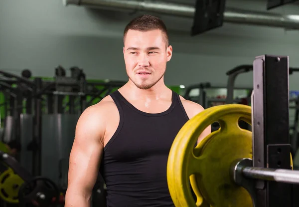 Mladý zdravý muž s velkými svaly drží disku závaží v tělocvičně. Fitness, sport, výcvik, motivace a životní styl koncepce — Stock fotografie