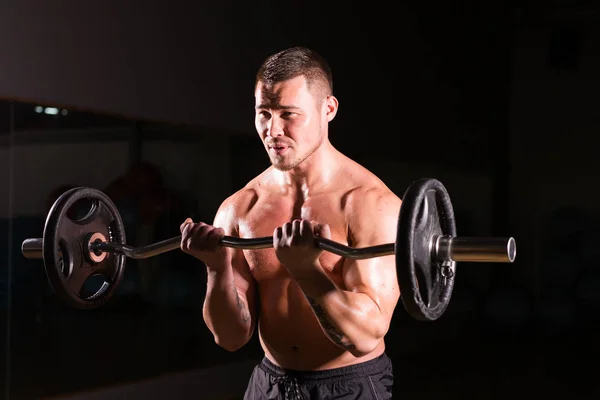 Svalnatý muž pracuje v tělocvičně dělá cvičení s činka na biceps, silný muž nahý trup abs — Stock fotografie