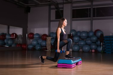 Sportif genç kadın ile güzel atletik vücut egzersizleri dumbbells ile yapıyor. Fitness, vücut geliştirme. Sağlık