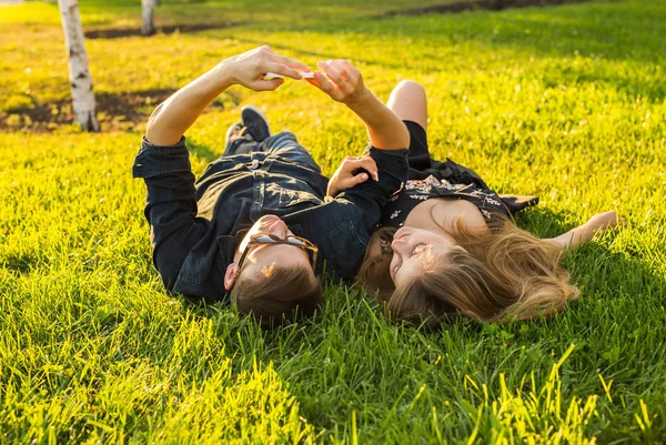 Amor e conceito de pessoas - casal adolescente feliz deitado na grama e tomando selfie no smartphone no verão — Fotografia de Stock