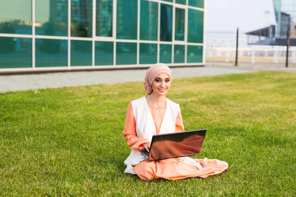 Başarılı Arap kadın ve laptop. Arap işkadını parkta bir dizüstü bilgisayar üzerinde çalışan hijab giyen. — Stok fotoğraf