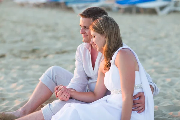 Jeune couple d'amour assis ensemble sur la plage — Photo