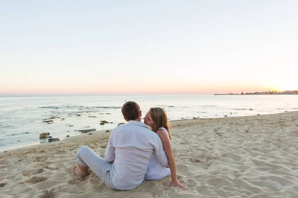 Молода пара кохання сидить разом на пляжі, вид ззаду — стокове фото