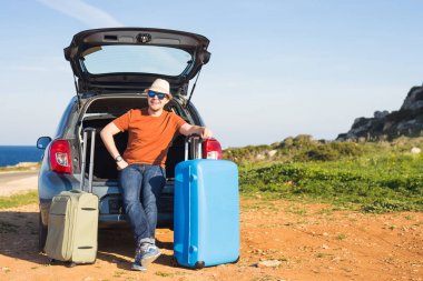 Seyahat, tatil, yaz gezisi ve insanlar kavramı - adam bavul bir arabanın içinde tatil oluyor